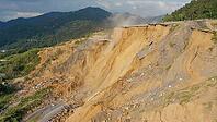 Landslide destroying asphalt road in mountain area creating deep chasm, causing traffic disruption and infrastructure damage, AI generated [IBR125653459]