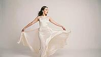 Fashion model dancing gracefully in an elegant long beige dress, showcasing beauty and style against a clean white studio background, AI generated [IBR125653470]