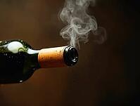 Wine bottle just opened with vapor escaping from the neck on a dark brown background, AI generated [IBR125653475]