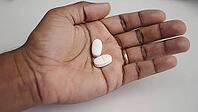 Open hand displaying two white pills, representing a concept of medical treatment and healthcare in a clinical setting, AI generated [IBR125653476]