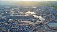 Aerial view capturing a vast landfill with bulldozers working diligently while birds soar overhead against a vibrant sunset backdrop, AI generated [IBR125653482]