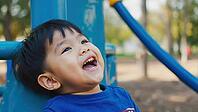 Candid portrait of a laughing preschooler enjoying playtime at a playground, expressing joy and happiness, AI generated [IBR125653483]