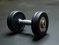 Heavy black dumbbell lying on gym floor, suggesting a challenging workout session focused on strength and fitness, AI generated [IBR125653489]