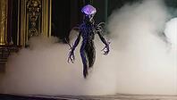 Extraterrestrial being walking onto a stage shrouded in smoke, set in a baroque style theater, creating an eerie, otherworldly atmosphere, AI generated [IBR125653491]