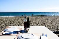 A covered restaurant table stands on the sunny sandy beach overlooking the sea, Estepona, Costa del Sol, Andalusia, Malaga province, Spain [IBR125657385]