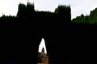 A narrow archway in a high hedge reveals the view of a historic tower, Church of Santa Maria de la Alhambra, Generalife, Garden of the Sultan, Jardín de la Sultana, Alhambra, Granada, Province of Granada, Andalusia, Spain [IBR125657456]