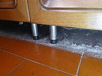 Dust on the floor under a base cabinet on legs [IBR125659399]