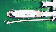 Abstract top-down aerial view of a modern Lake Constance car ferry at the Meersburg ferry terminal. The white ferry lies precise at the ramps of the harbour structure while vehicles parked on the deck are visible. The water of the lake shimmers in bright  [IBR125659416]