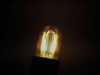 Bright LED filament light bulb over dark background [IBR125659436]