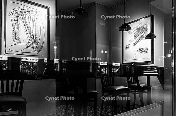 Black and white photograph, urban scene in the evening with reflections of Friedrichstraße in the window pane of a bistro, Berlin, Germany [IBR112672621]