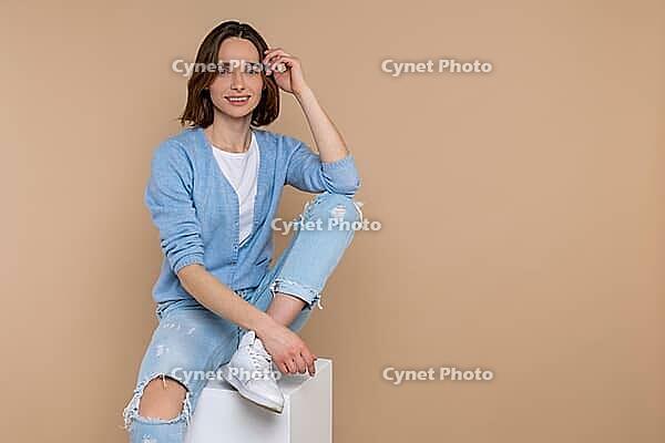 Smiling fashion woman in casual clothing looking at camera with happy face empty space isolated over beige background [IBR123569310]