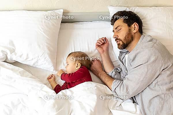 Father and little baby sleeping together in bed, parenthood, newborn daughter [IBR123569317]