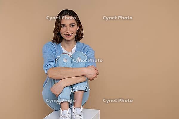Confident attractive woman in casual clothing looking at camera isolated over beige background [IBR123569335]