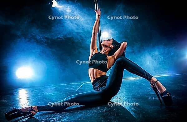 Young sexy woman pole dancing on dark background with smoke [IBR123569351]