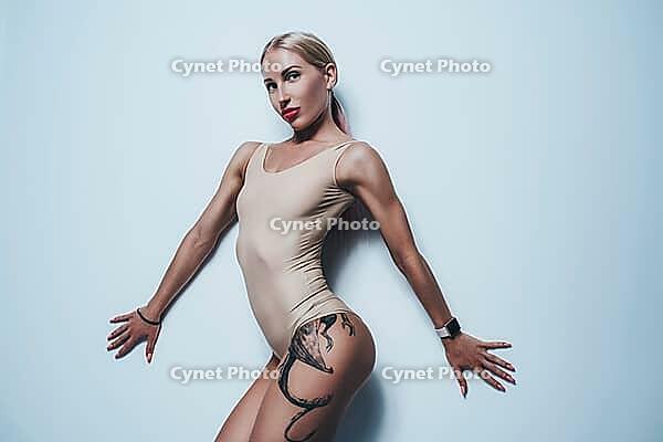 Young sexy blond woman in white lingerie portrait on white wall background. Tattoo on body [IBR123569353]