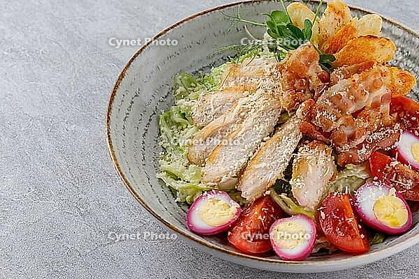 Food, Caesar salad with chicken and croutons on a gray background on a plate, photo for restaurant menu [IBR123622461]