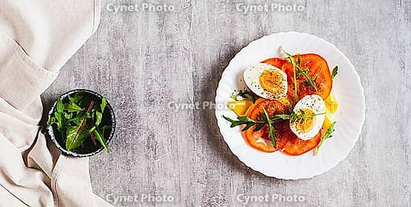 Tomato slices, egg, cheese and herbs on a plate on the table top view web banner [IBR123629691]