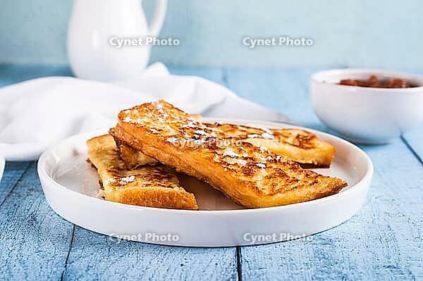 Appetizing croutons in powdered sugar on a plate on the table [IBR123629712]
