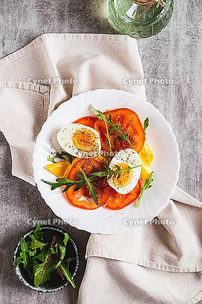 Tomato slices, egg, cheese and herbs on a plate on the table top and vertical view [IBR123629713]