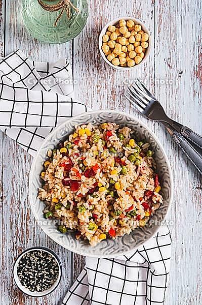 A bowl of cooked rice and vegetables for garnish on the table top and vertical view [IBR123629721]