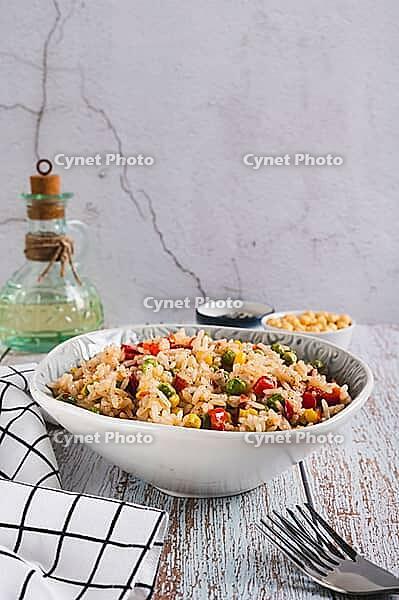 Homemade fried rice with peas, corn and pepper in a bowl on the table vertical view [IBR123629722]