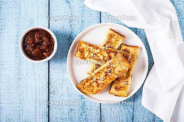 Appetizing croutons in powdered sugar on a plate on the table top view [IBR123629724]