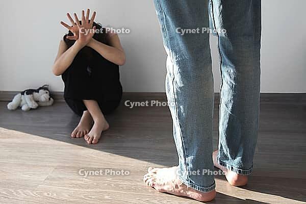 Child girl 7-8 years old sits on floor scared, covering her face with her hands, stands angry man whose face is not visible, father or stepfather, concept of violence, punishment of children [IBR123638378]