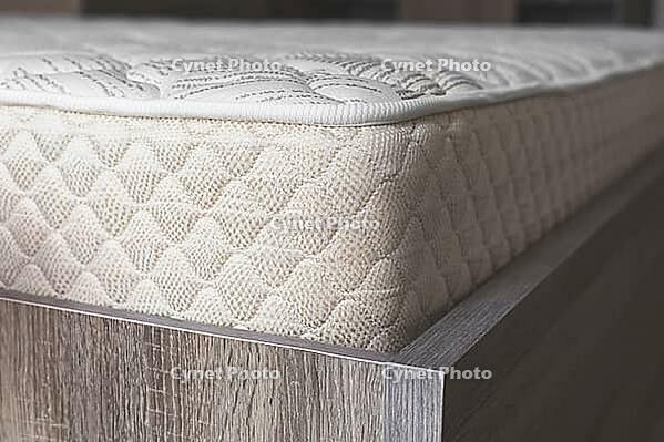 Comfortable orthopedic mattress with a quilted surface on a wooden bed frame, showcasing high-quality fabric texture and ergonomic design for restful sleep [IBR123638380]