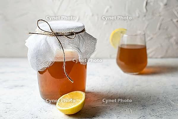 Raw fermented homemade alcoholic or non alcogolic kombucha superfood. Ice tea with healthy natural probiotic in glass with lemon slice on white background [IBR123639493]