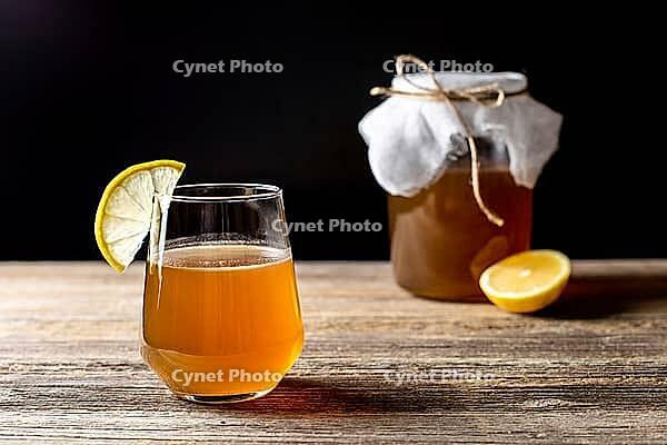 Raw fermented homemade alcoholic or non alcogolic kombucha superfood. Ice tea with healthy natural probiotic in glass with lemon slice on wooden background [IBR123639495]