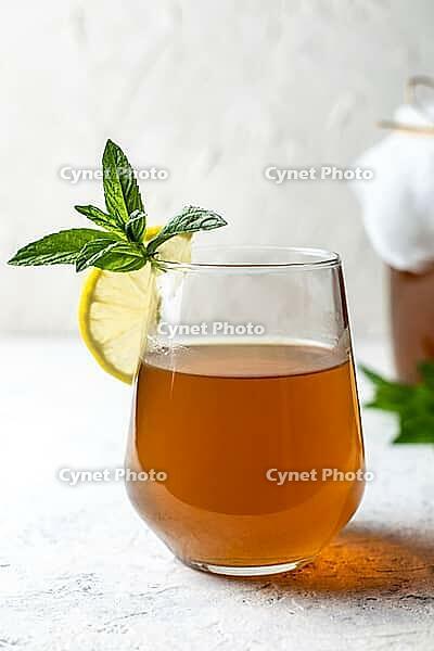 Raw fermented homemade alcoholic or non alcogolic kombucha superfood. Ice tea with healthy natural probiotic in glass with lemon slice and mint on white background [IBR123639496]