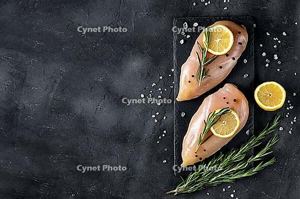 Raw fresh chicken fillet with rosemary, lemon and spices on a dark background. Food background, cooking ingredients. Top view with copy space [IBR123639513]