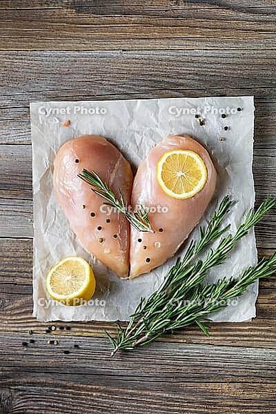 Raw chicken fillet in the shape of a heart with rosemary and spices on natural wooden background. Top view [IBR123639517]