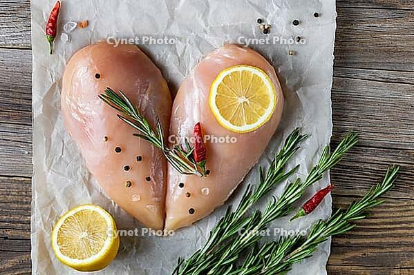 Raw chicken fillet in the shape of a heart with rosemary and spices on natural wooden background. Top view [IBR123639518]