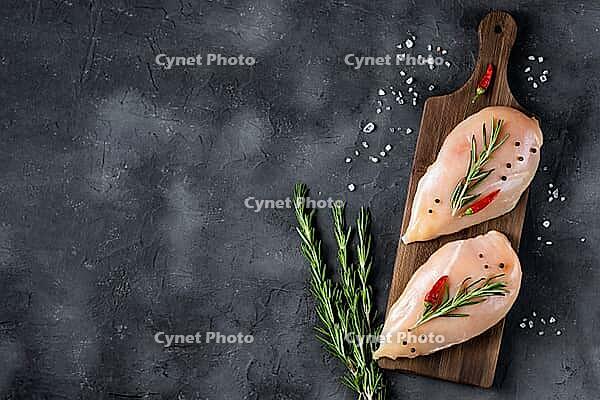 Raw fresh chicken fillet with rosemary and spices on a dark background. Food background, cooking ingredients. Top view with copy space [IBR123639520]
