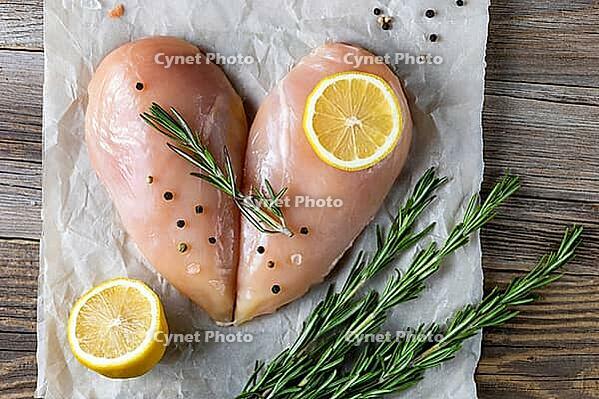 Raw chicken fillet in the shape of a heart with rosemary and spices on natural wooden background. Top view [IBR123639521]