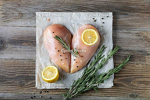 Raw chicken fillet in the shape of a heart with rosemary and spices on natural wooden background. Top view [IBR123639522]