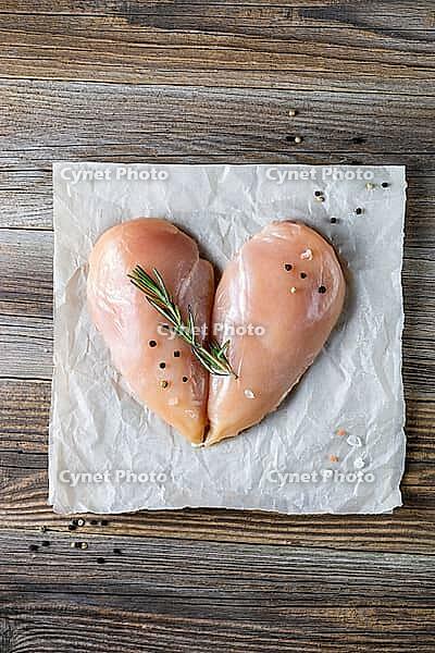 Raw chicken fillet in the shape of a heart with rosemary and spices on natural wooden background. Top view [IBR123639525]