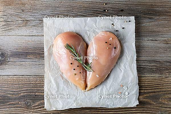 Raw chicken fillet in the shape of a heart with rosemary and spices on natural wooden background. Top view [IBR123639526]