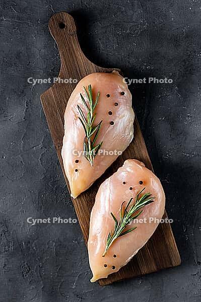 Raw fresh chicken fillet with rosemary and spices on a dark background. Food background, cooking ingredients. Top view [IBR123639527]