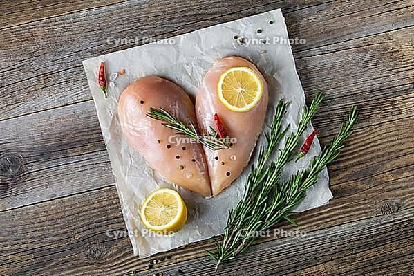 Raw chicken fillet in the shape of a heart with rosemary and spices on natural wooden background. Top view [IBR123639528]