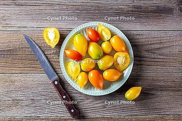 Various colorful ripe tomato on wooden background. Cooking from yellow orange and red cherry tomatoes. Top view with copyspace [IBR123639567]