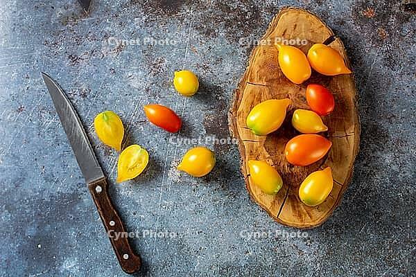 Various colorful ripe tomato on rustic blue background. Cooking from yellow orange and red cherry tomatoes. Top view [IBR123639568]