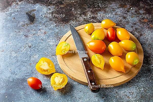 Various colorful ripe tomato on rustic blue background. Cooking from yellow orange and red cherry tomatoes. Top view [IBR123639573]