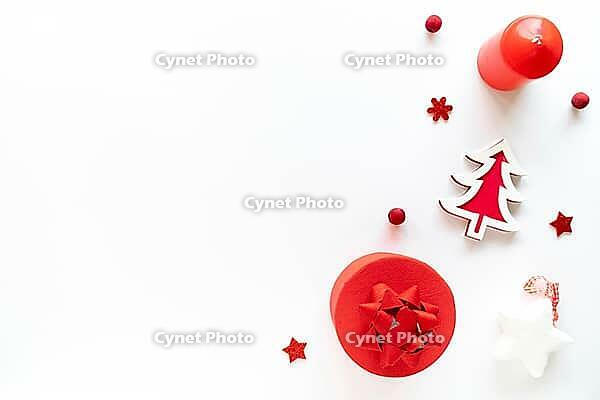 Christmas art composition with red decor, gift box and candle on white. Chritmas eve, noel, gift concept. Flat lay, top view, copy space [IBR123646466]