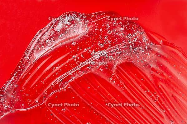 Cosmetic gel smudge with bubble. Transparent skincare product on red. Liquid lotion splash. Serum gel. Hyaluronic acid smear. Lubricant sample. Moisturiser with vitamin. Sexy jelly texture [IBR123646468]