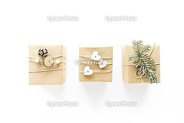 Christmas handmade gift boxes art composition on white surface. Gifts, christmas wooden decorations, fir branches, pine cone. Handmade DIY concept. Flat lay, top view, above [IBR123646492]