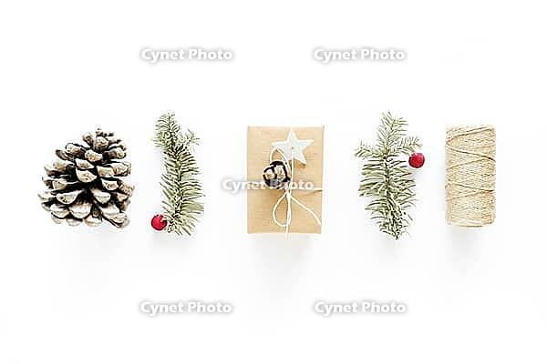 Christmas gift art composition on white surface. Gifts, christmas wooden decorations, fir branches, pine cone. Handmade DIY concept. Flat lay, top view. Winter flatlay holiday background [IBR123646493]