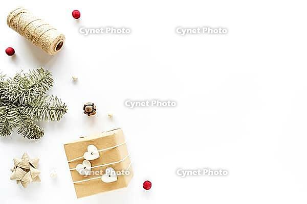 Christmas composition on white surface. Handmade present, holiday decorations, fir branches, pine cone. Christmas DIY concept. Flat lay, top view, copy space [IBR123646495]