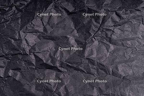 Dark wrinkled creased black paper poster texture. Blank creased crumpled grainy paper textured surface. Smudged grungy cardboard with fiber. Close up. Material tissue for packing [IBR123646512]